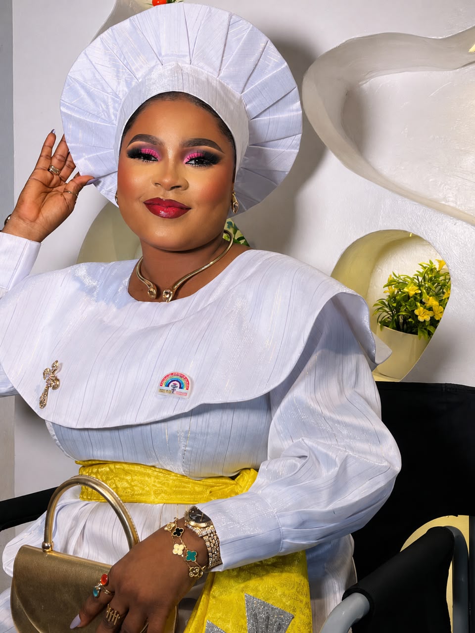White outfit with pleated headwrap and gold bag